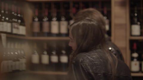 A man and woman look at bottles of wine