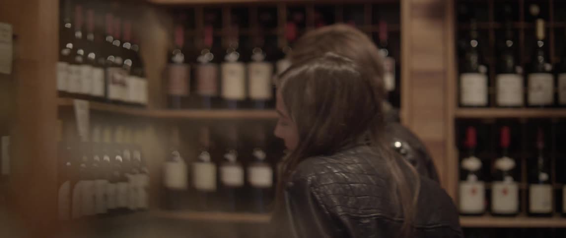 A man and woman look at bottles of wine