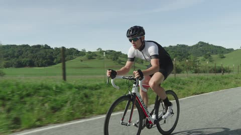 A man riding a ten speed down a road in a rural area