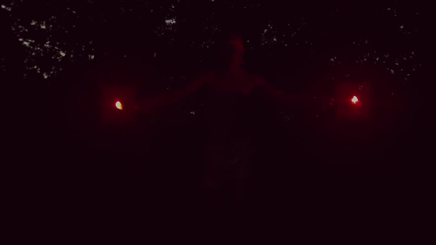 A person holding flares and slowly raising them in the air