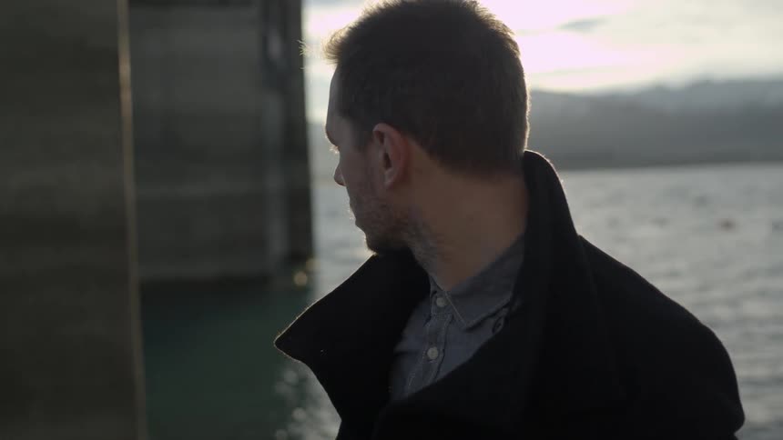 A man turns his head at the sunset on the water's edge