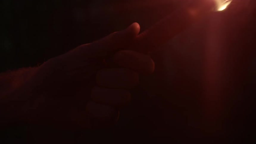 Someone holds a burning flare at night