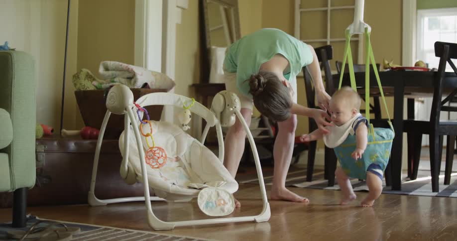 A woman tends to a baby in a jumping swing