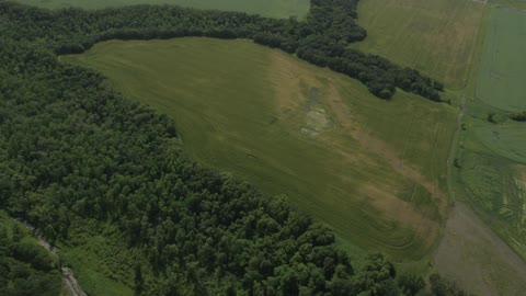 An aerial view of a field, trees and a river