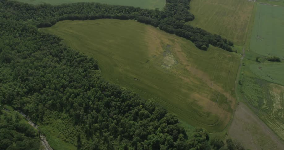 An aerial view of a field, trees and a river