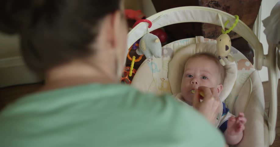 Woman spoon feeds her baby inside their house