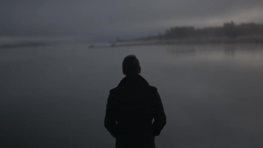 Man stands in front of misty lake