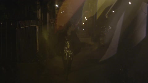 A person walking down a sidewalk at night