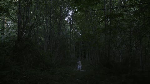 A man stands in his underwear in the woods