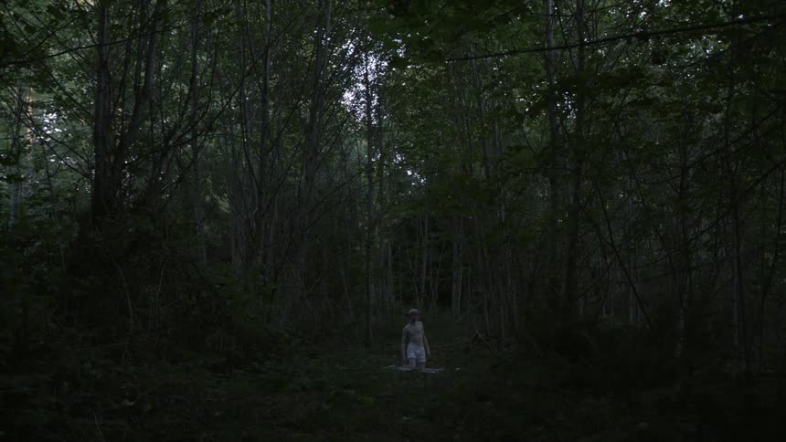 A man stands in his underwear in the woods
