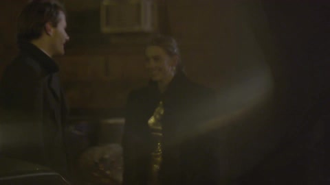 Man smiles as woman in gold dress walks up