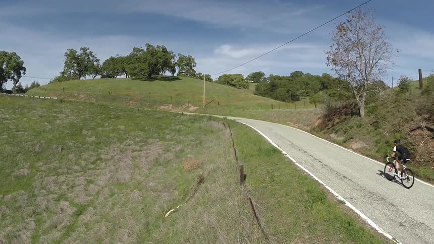 A man riding a ten speed uphill in a rural area