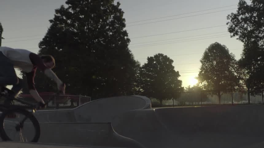 A man on a bicycle rides through a skatepark