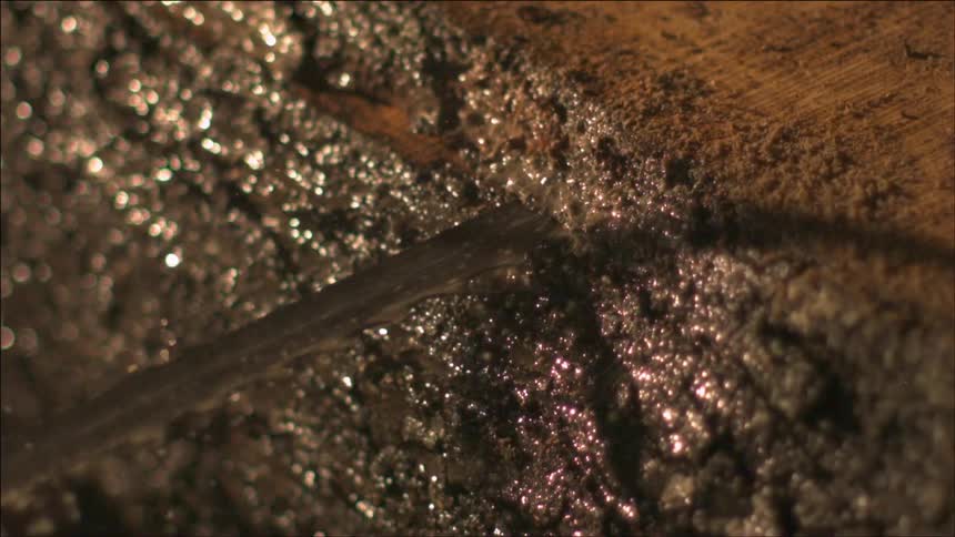 Closeup of a thin rivulet of water flowing over mud