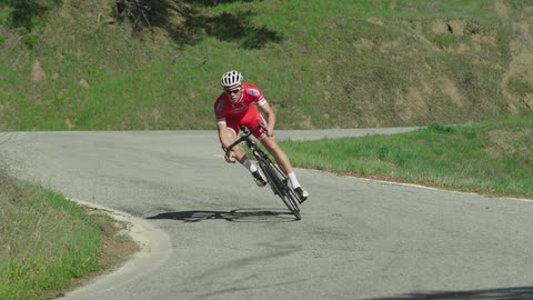 A man riding a ten speed down a winding road in a rural area