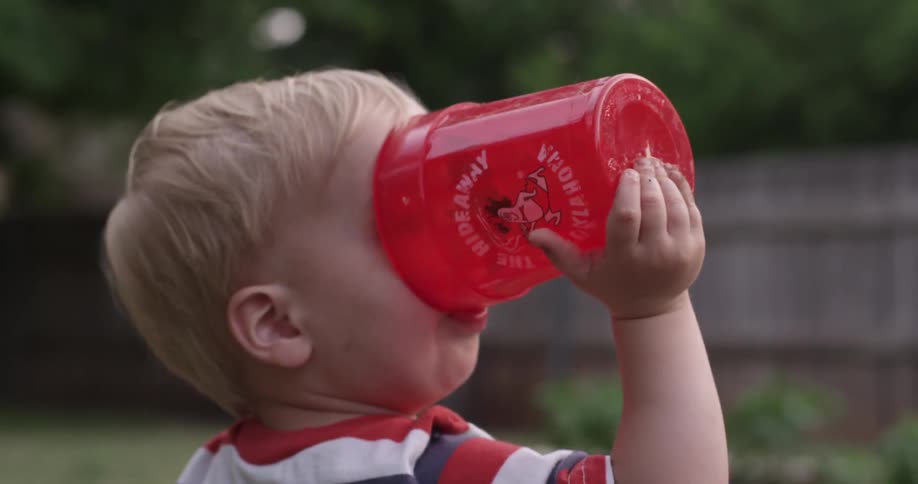A boy drinks out of a cup