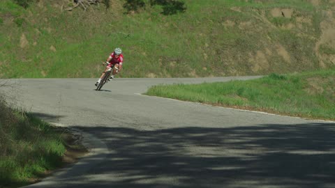 A man riding a ten speed down a winding road in a rural area