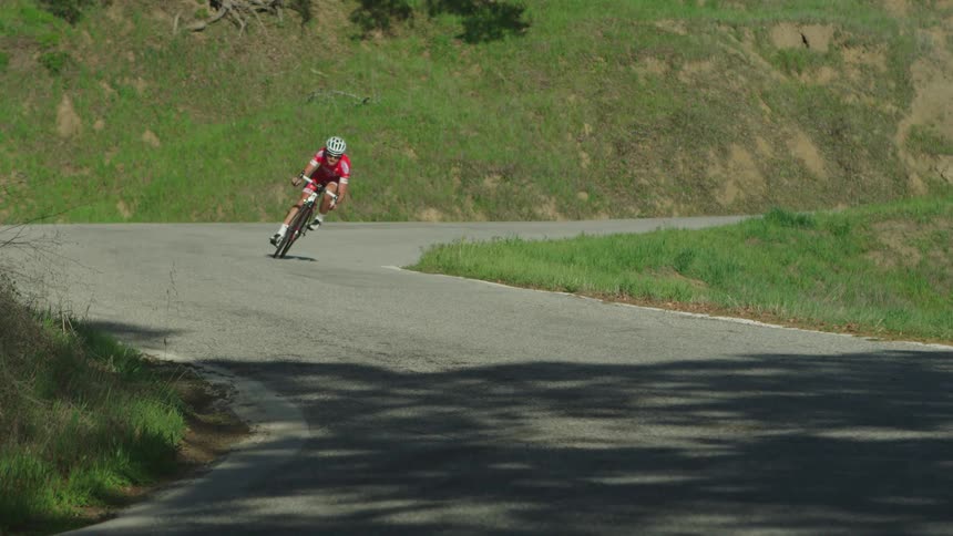 A man riding a ten speed down a winding road in a rural area