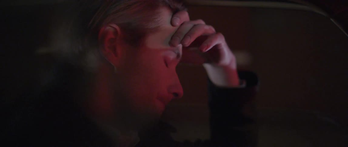 A young man rubbing his face, closing his eyes and shaking his head before muttering something