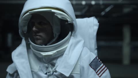 A person in an astronaut costume wandering an empty urban area at night