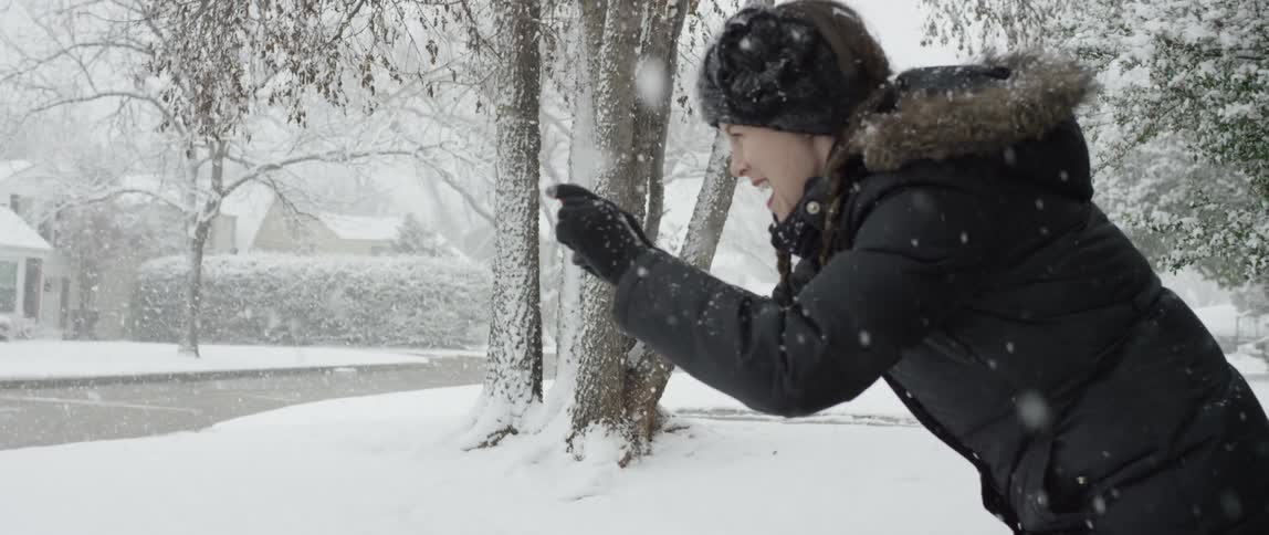 A smiling woman takes a picture while it's snowing