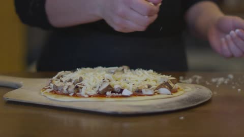 A female is shown preparing a pizza