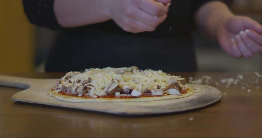 A female is shown preparing a pizza