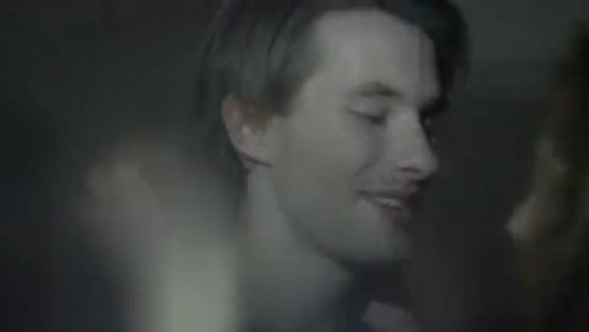 A young couple dance with flashing lights in the background
