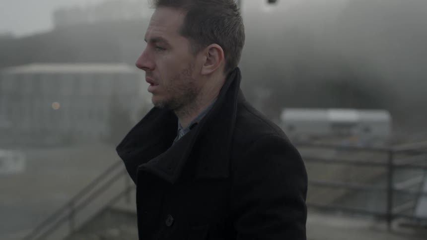 A man walks on the sidewalk on a foggy day