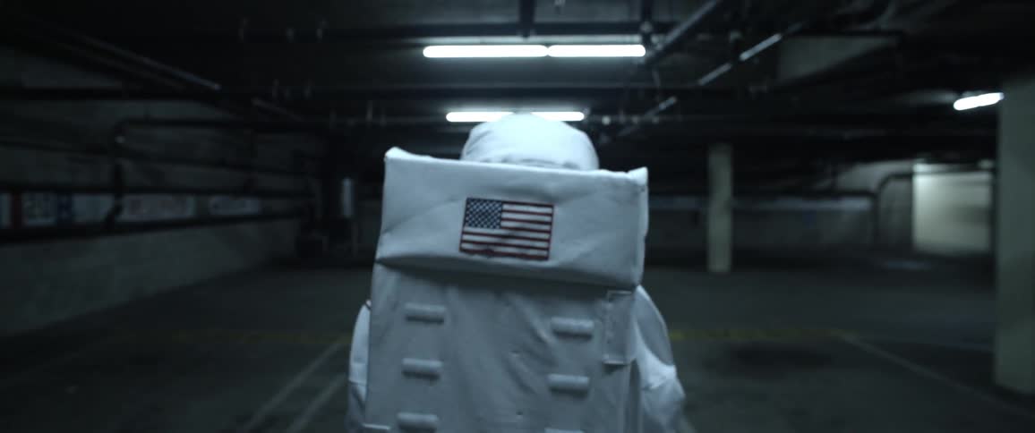 Man in astronaut suit walks in an underground parking garage