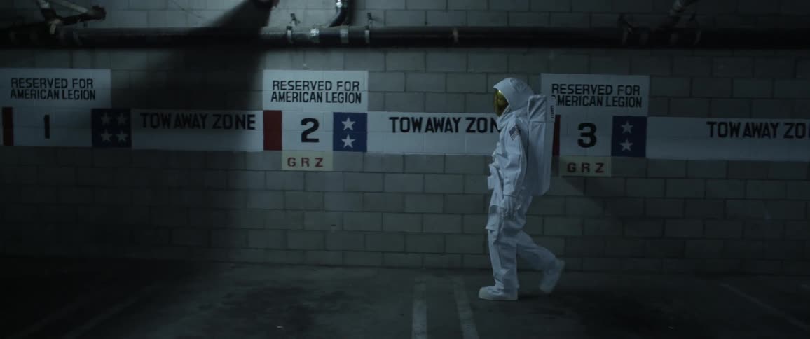 A person in a spacesuit walking past white signs