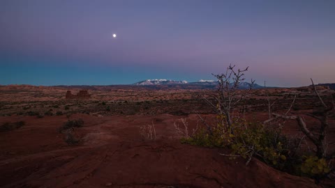 A desert with a colorful sky going from light to dark