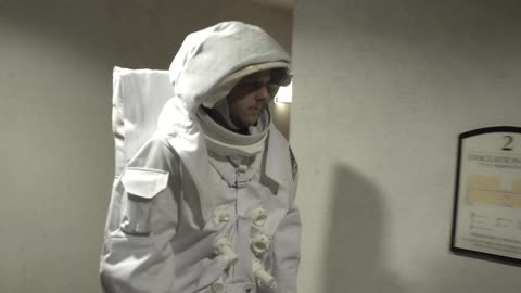 A person in an astronaut costume walking down a hallway