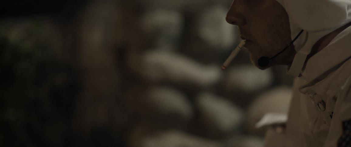 A person wearing a white hood is smoking a cigarette