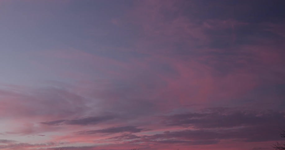 Blue and pink clouds slowly pass by, speeded up with timelapse