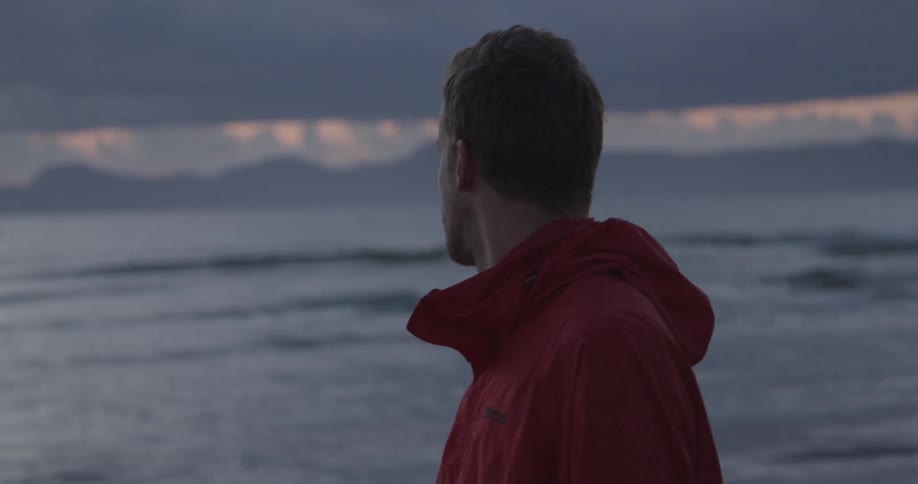 Man standing on the beach looking at the water