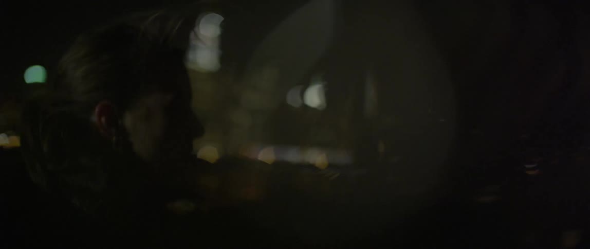 A woman woman smokes and waves someone off on a windy night
