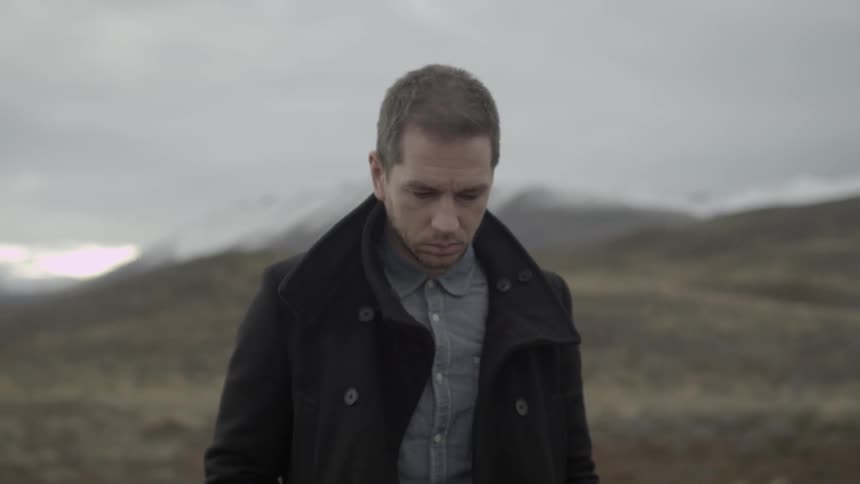 A depressed looking man walks alone in a remote region