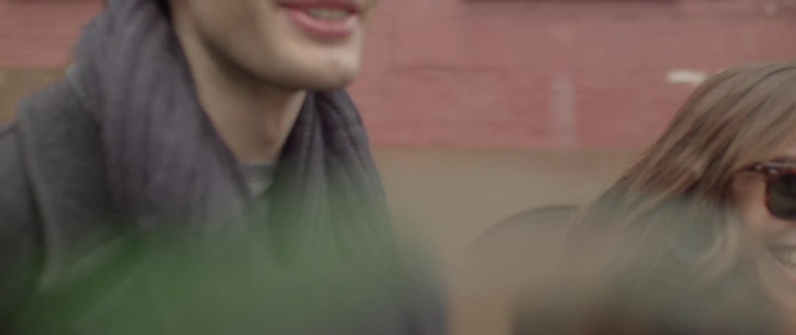 A man and a woman walking down a city street laughing and talking before she puts her head on his chest