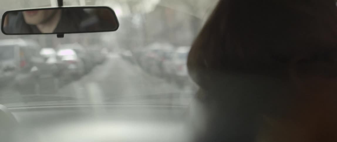 A blonde man driving a car down a city street