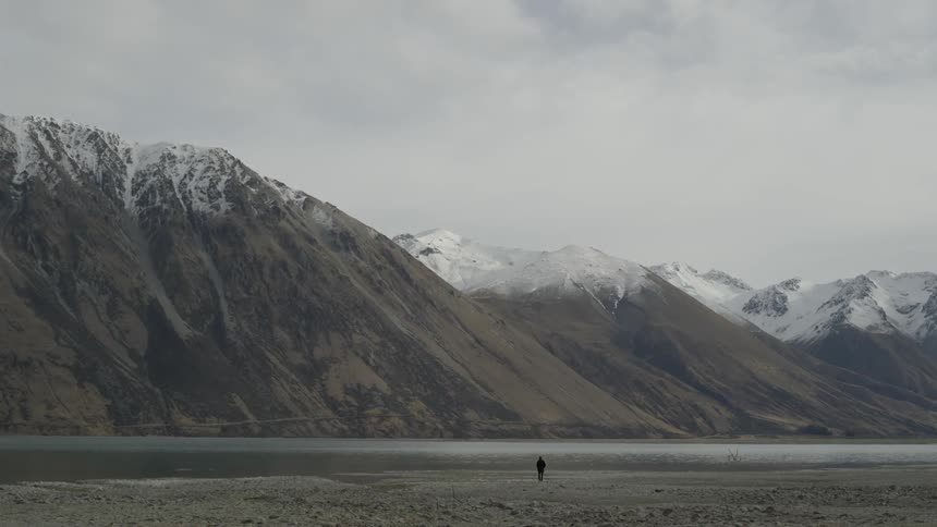 Person walking towards mountains on a cloudy day