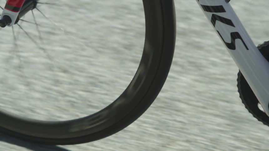 A view of a man's feet as he pedals a white bike