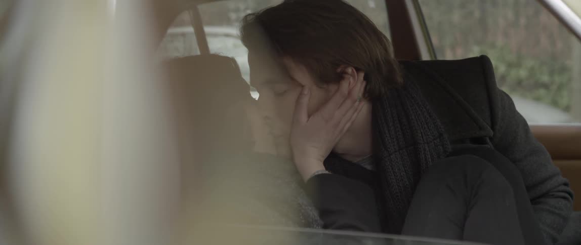 A person sitting inside of a car and kissing someone else