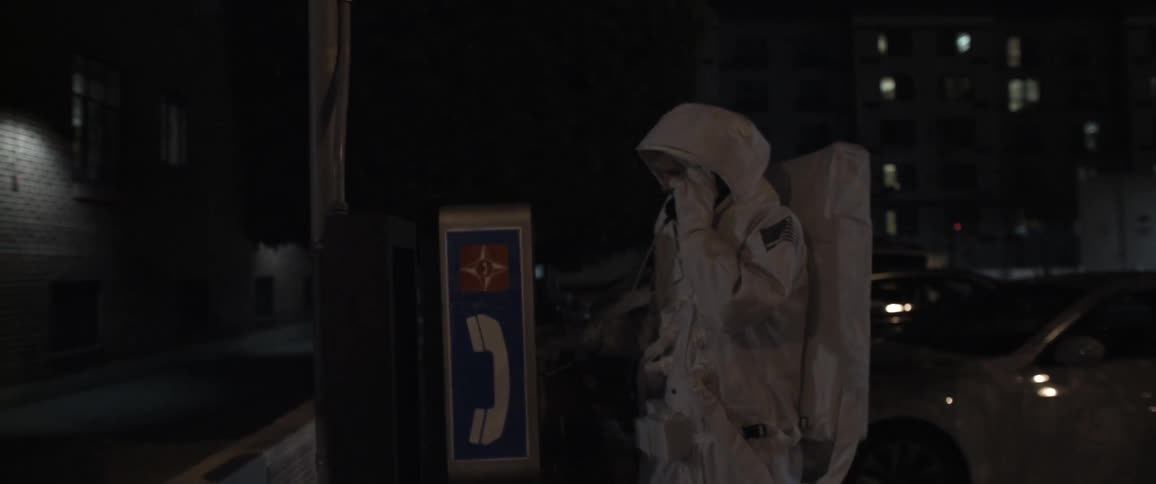 A man in an astronaut costume uses a phone booth