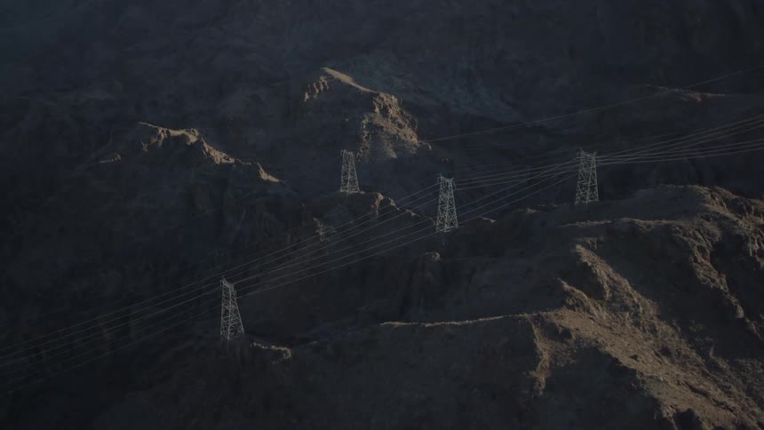 A view of electric lines and towers that are located on top of mountain cliffs