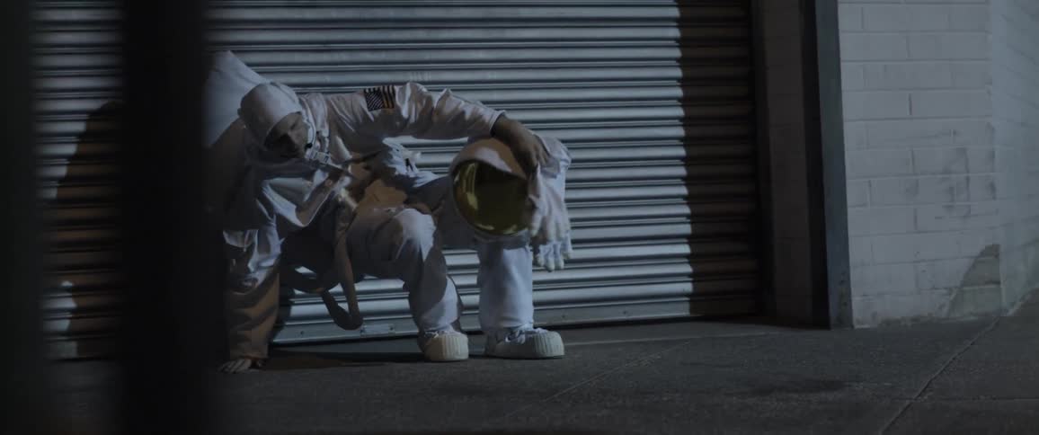 An astronaut stands up from where he is seated on the ground