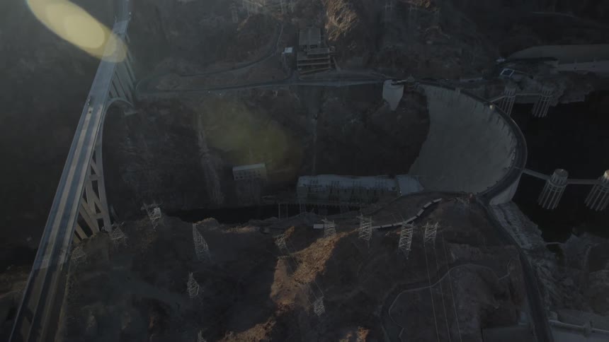 An aerial view of a bridge that crosses a deep gorge near a dam