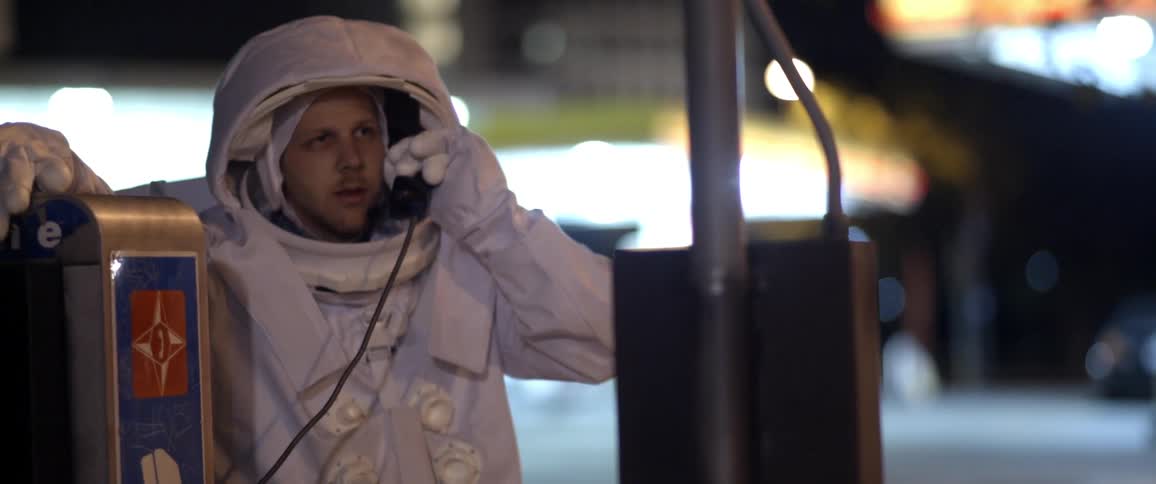 A person wearing an astronaut costume uses a pay phone