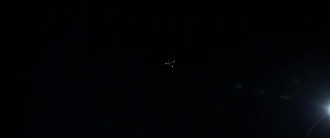 A plane flies in a dark night sky