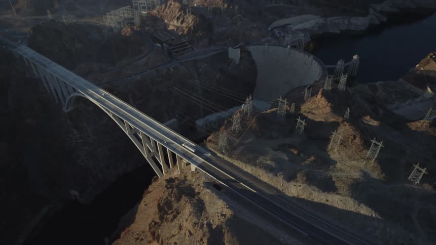 Traffic on a bridge crossing a canyon river located next to a dam